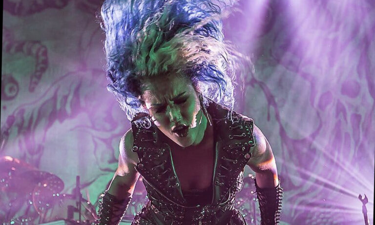 Sängerin Alissa White-Gluz von Arch Enemy steht mit blauen Haaren und Mikrofon auf der Bühne beim Live-Konzert im E-Werk in Köln vor feierndem Publikum.