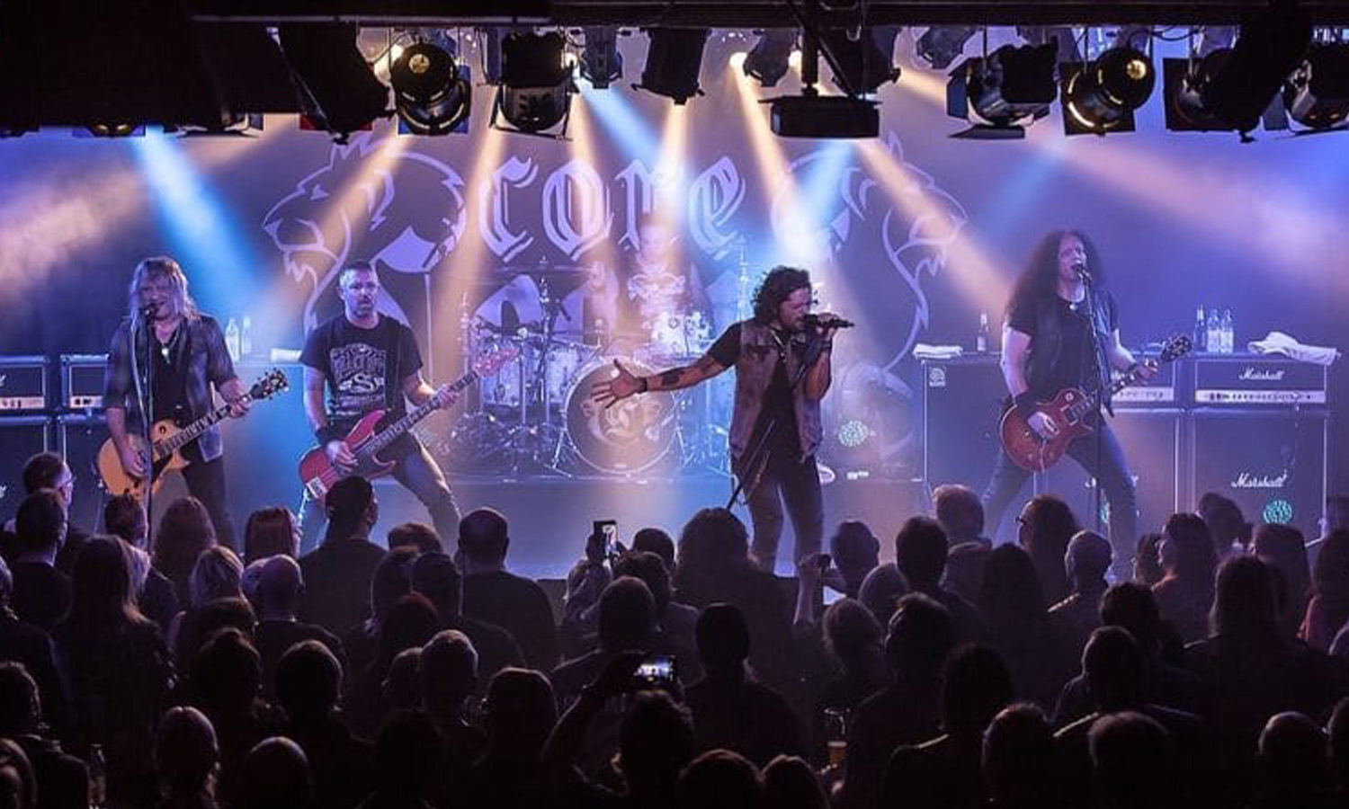 Die Hard-Rock-Band CoreLeoni um Gitarrist Leo Leoni und Sänger Ronnie Romero performt energiegeladen mit Instrumenten vor Publikum.